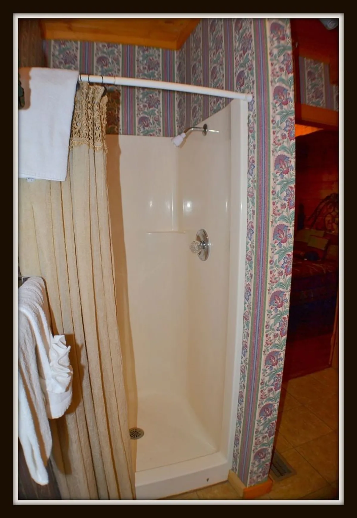 A well-appointed ensuite bathroom showcasing a modern walk-in shower, decorative wallpaper, and neatly arranged towels. The space is bright, inviting, and designed for rejuvenation after a day of adventure.